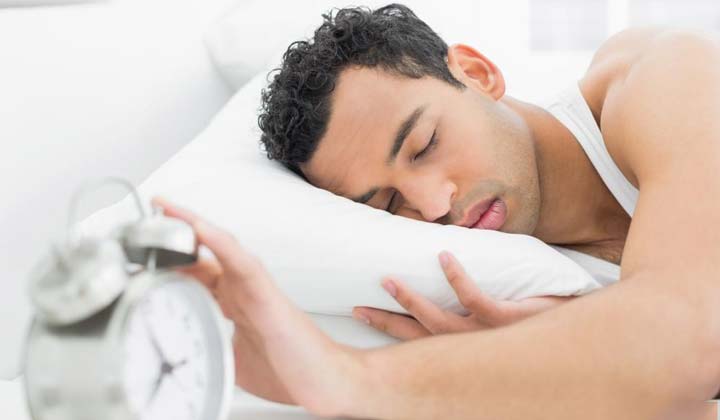 man-asleep-on-pillow-with-hand-on-alarm-clock-1.jpg