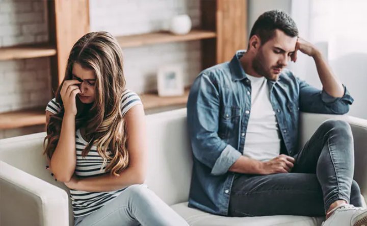 Two people sitting on the sofa in a sad state